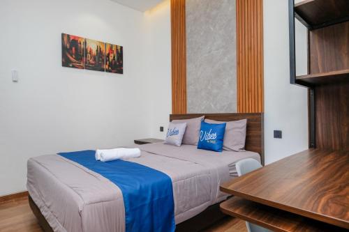 una camera da letto con un letto con cuscini blu e un tavolo di Vibes Djanti Residence Yogyakarta By Sans Hotel a Demangan