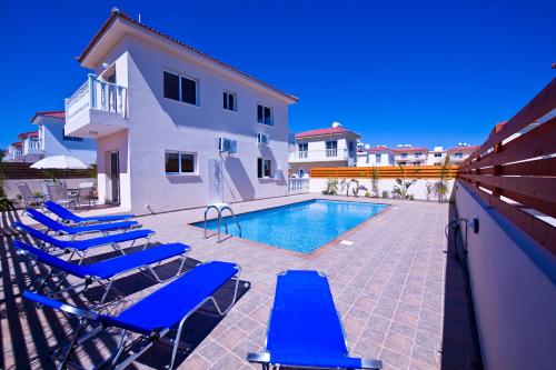 a swimming pool with blue lounge chairs next to a house at Villa Agnes in Ayia Napa