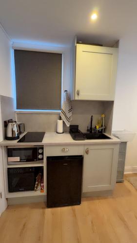 a small kitchen with white cabinets and a sink at Cosy central studio close to local attractions in London