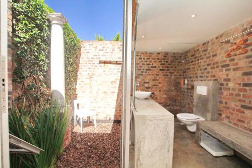a bathroom with a toilet and a brick wall at Motel Mi Pi Chi in Johannesburg