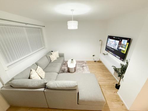 a living room with a gray couch and a flat screen tv at Modern 3BR House Near Bolton & Manchester in Farnworth