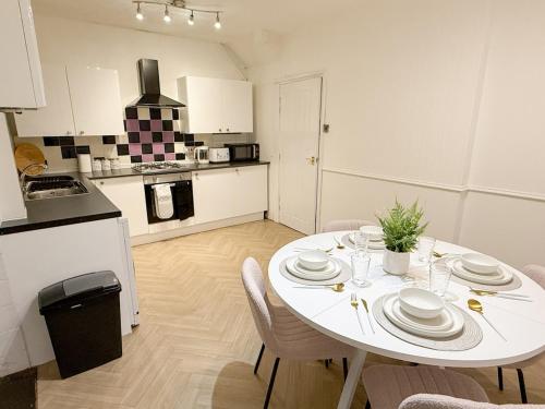 a white kitchen with a white table and chairs at Modern 3BR House Near Bolton & Manchester in Farnworth
