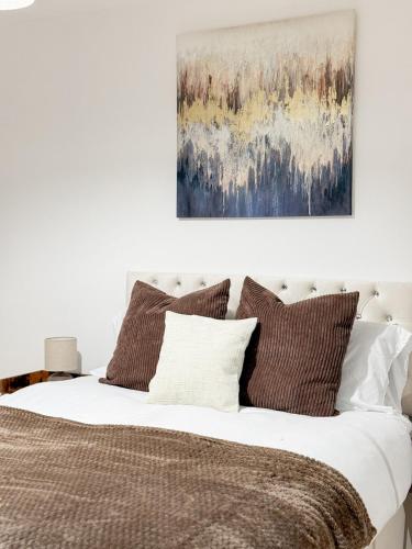 a bed with brown pillows and a painting above it at Modern 3BR House Near Bolton & Manchester in Farnworth