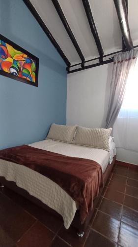 ein Bett in einem Zimmer mit einem Gemälde an der Wand in der Unterkunft CASA NOCHE AZUL alojamiento turístico in Villa de Leyva
