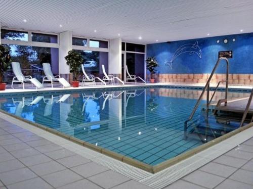 una grande piscina con sedie bianche in un edificio di Ferienwohnung Sonnenschein mit Pool und Sauna a Lahnstein