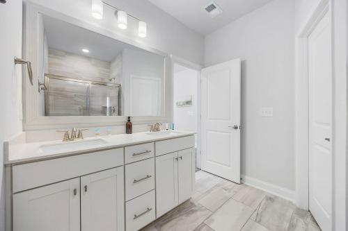 a white bathroom with two sinks and a mirror at Birdie Bungalow- Games Beach Gear Sleeps 10 in Myrtle Beach