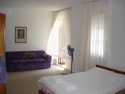 a bedroom with a bed and a purple couch at Villa Rhapsody Pension in Kayakoy