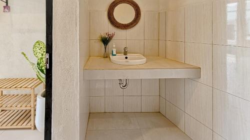 een badkamer met een wastafel en een spiegel aan de muur bij KAYA Uluwatu in Uluwatu