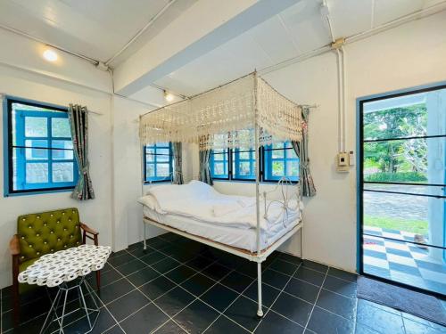 een slaapkamer met een hemelbed en een stoel bij Today Sunset ที่พักวังน้ำเขียว in Ban Nong Chaeng