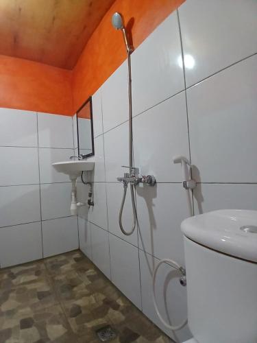 a bathroom with a shower and a toilet and a sink at meta bungalow in Senaru