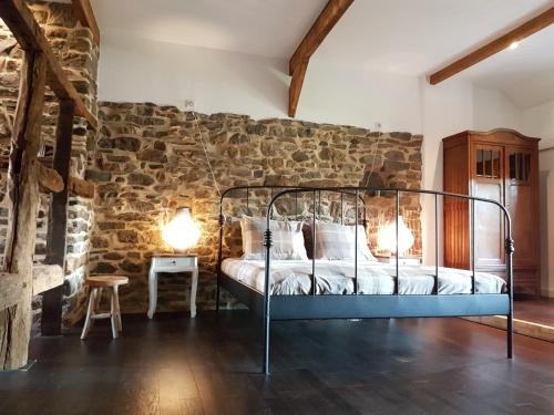 1 dormitorio con 1 cama en una pared de piedra en La Ferme de Spa en Spa