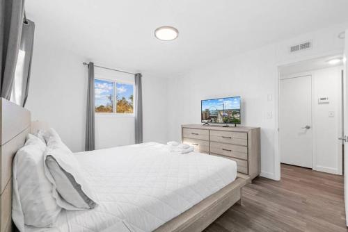 a white bedroom with a large bed and a window at Azul Condos - Ocean steps away - Full Kitchen in Myrtle Beach