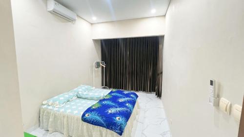 una camera da letto con un letto con una coperta blu sopra di Teem Living Jogja a Jejeran