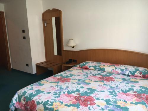 a bedroom with a bed with a floral bedspread at Garni Enrosadira in Vigo di Fassa