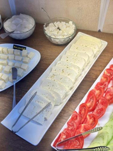 ein Holztisch mit Käse, Tomaten und anderen Lebensmitteln in der Unterkunft Hotel Nebula Inn in Tbilisi City