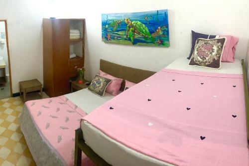 una camera con due letti con lenzuola rosa di Hotel Casa de Sarah a Santa Marta