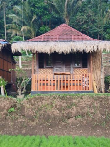 een kleine hut met een rieten dak op een veld bij meta bungalow in Senaru