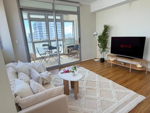 a living room with a white couch and a tv at Burwood Luxe Urban Escape in Sydney