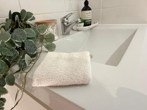 a white sink with a towel and a potted plant at Burwood Luxe Urban Escape in Sydney