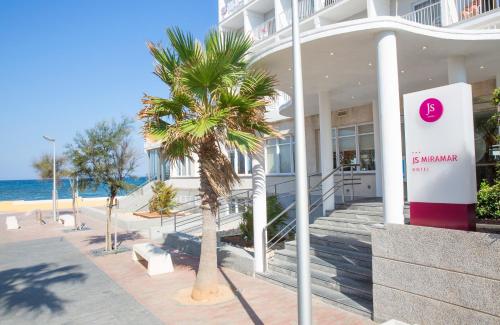 a building with a palm tree in front of it at JS Miramar in Can Picafort