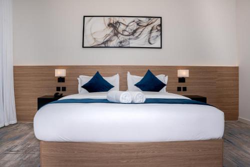 a bedroom with a large white bed with blue pillows at ارجان بارك الحمراء in Riyadh