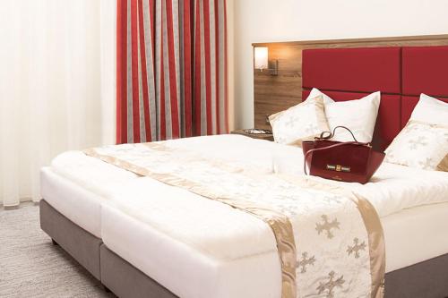 a hotel room with a large bed with a purse on it at Naam Apartment Frankfurt Hotel City-Airport in Frankfurt