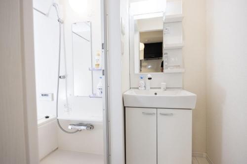 a white bathroom with a sink and a shower at Ikebukuro House-TS0378 in Tokyo