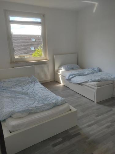 twee bedden in een kamer met een raam bij Ganze Wohnung mit privatem Balkon in Gelsenkirchen
