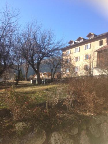 a building on a hill with trees in the background at Garni Enrosadira in Vigo di Fassa