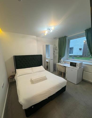 a bedroom with a bed and a desk and a window at Dancenter Tolcarne Beach hotel in Newquay