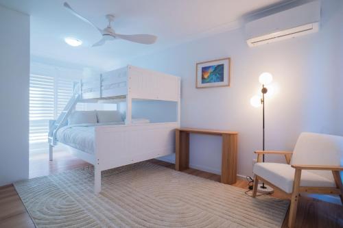 a bedroom with a white bunk bed and a chair at Paws & Palms Hideaway in Nelson Bay