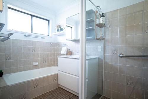 a bathroom with a tub and a sink and a shower at Paws & Palms Hideaway in Nelson Bay