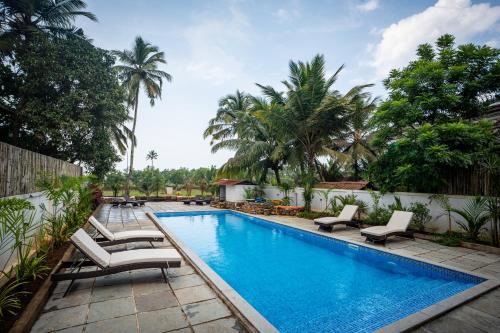 a swimming pool with chaise lounge chairs next to a resort at Mistral by the sea in Benaulim