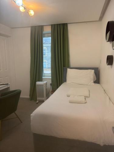 a bedroom with a white bed with a chair and a window at Dancenter Tolcarne Beach hotel in Newquay