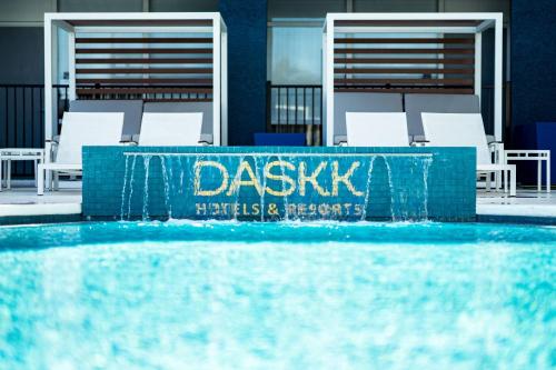 a swimming pool with white chairs and a blue wall at DASKK Orlando Hotel near Universal Blvd, an Ascend Collection Hotel in Orlando