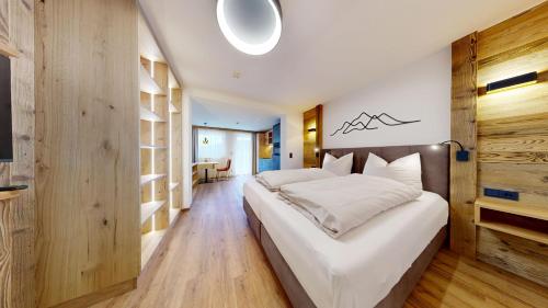 a bedroom with a large white bed and wooden floors at Moonlight Apartments in Söll