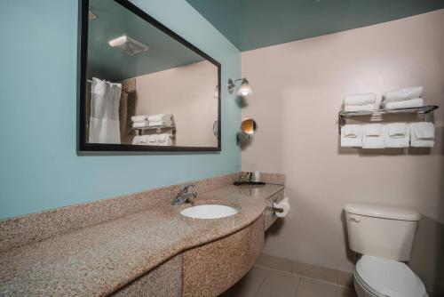 a bathroom with a sink and a mirror and a toilet at Gateway Hotel & Suites, an Ascend Collection Hotel in Ocean City