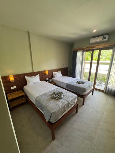 een hotelkamer met twee bedden en een raam bij Hepy Hotel in Kuta Lombok