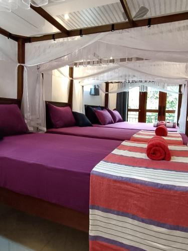 two beds in a room with purple and purple sheets at Villa Four Seasons in Mirissa