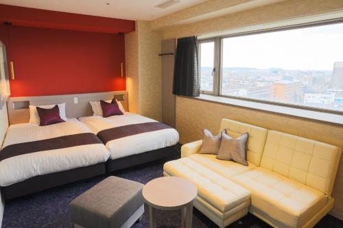 ein Hotelzimmer mit zwei Betten und einer Couch in der Unterkunft Hotel Castle Inn Suzuka in Suzuka