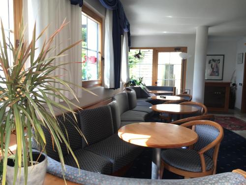 a waiting room with tables and chairs and plants at Garni Enrosadira in Vigo di Fassa