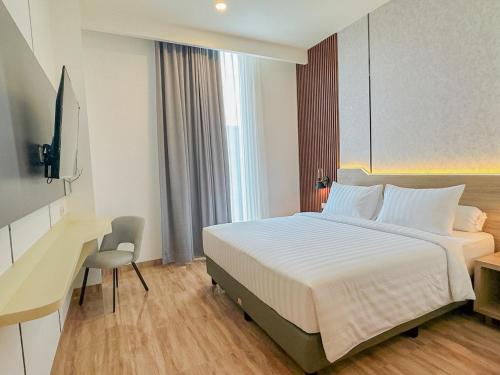 a hotel room with a large bed and a desk at Azana Style Hotel Jombang in Peterongan