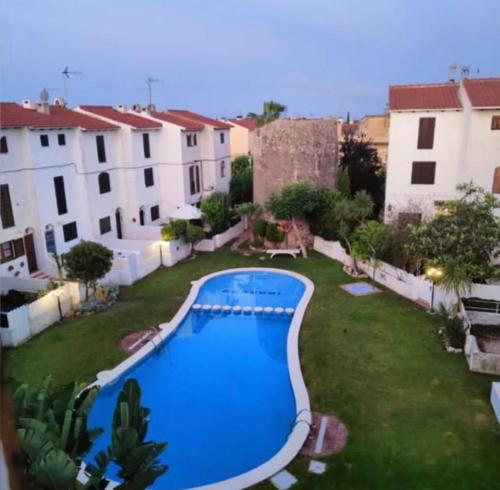 una piscina nel mezzo di un cortile con edifici di Acogedor adosado con piscina a Torredembarra