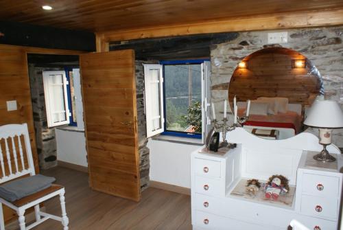 a bedroom in a log cabin with a bed and windows at Casa do Terreiro in Pardieiros