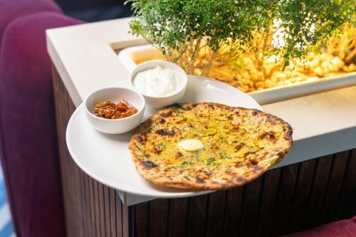 einen Teller Essen mit einer Pizza auf dem Tisch in der Unterkunft The Madelinne Hotel in Muzaffarnagar