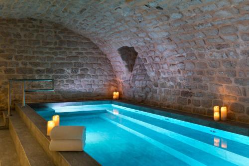 - une piscine dans un ancien bâtiment avec un mur en briques dans l'établissement Hôtel Square Louvois, à Paris