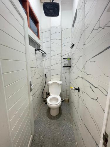 a bathroom with a white toilet in a stall at Utama Guest House Kuta Alam in Banda Aceh