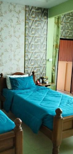 a bedroom with a blue bed with a wall at บ้านพักสายรุ้ง เพรชรบุรี in Tha Chang