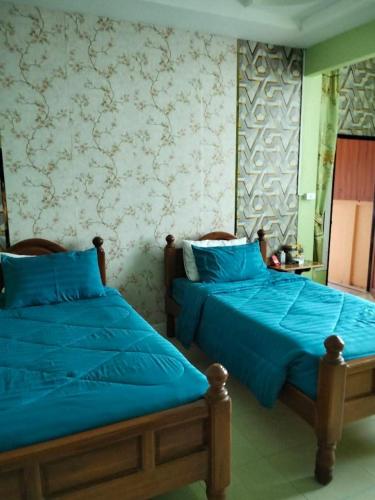 two beds sitting next to each other in a bedroom at บ้านพักสายรุ้ง เพรชรบุรี in Tha Chang