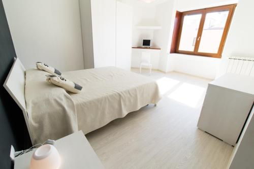 a white bedroom with a bed and a window at Casa Roncalli in Foligno